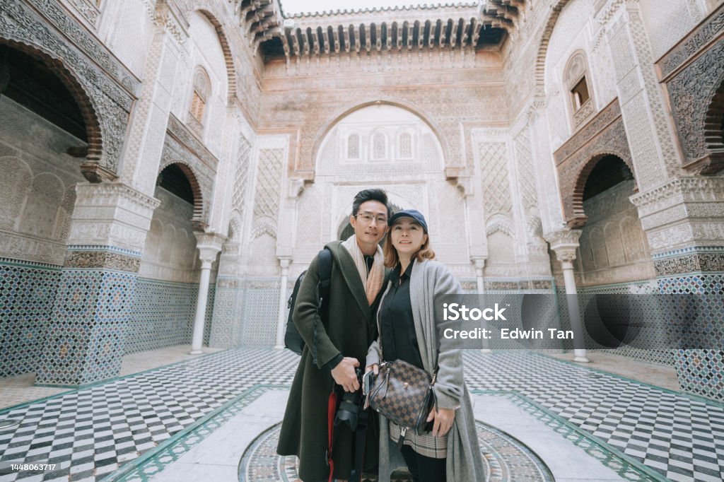 Asian Chinese tourist couple looking at camera standing at Fez Mosque Bou Inania Madressa Morocco Stock Photo