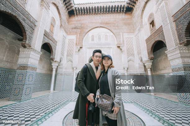 Asian Chinese Tourist Couple Looking At Camera Standing At Fez Mosque Bou Inania Madressa Stock Photo - Download Image Now