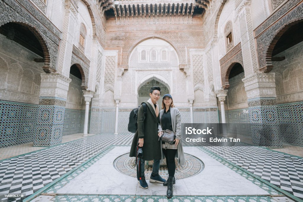 Asian Chinese tourist couple looking at camera standing at Fez Mosque Bou Inania Madressa Adults Only Stock Photo
