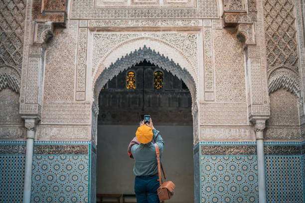 Asian Chinese female tourist photographing and admiring Fez Mosque Bou Inania Madressa stock photo