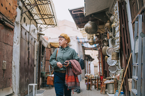 Asian Chinese female tourist walking in Traditional Handmade Brass Store  at Fez,  Morocco, Africa.