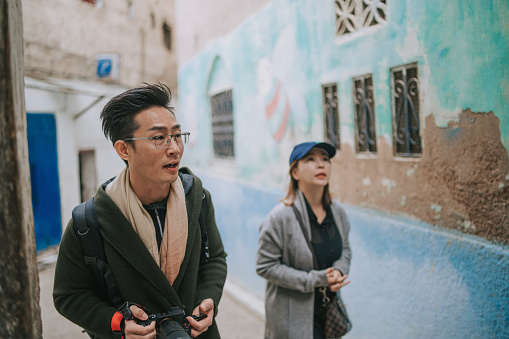 Asian Chinese couple tourist walking into narrow alley in the old medina of Fez, Morocco