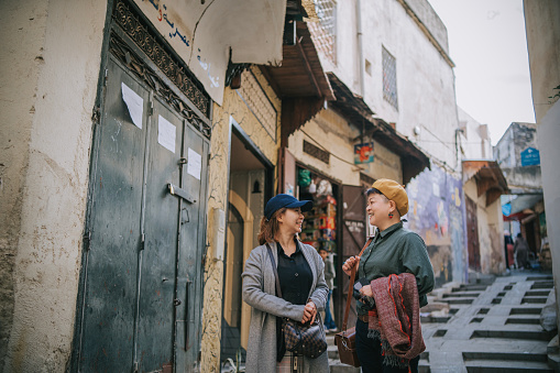 2 Asian Chinese female tourist exploring souk market streets of old town Fez, Morocco