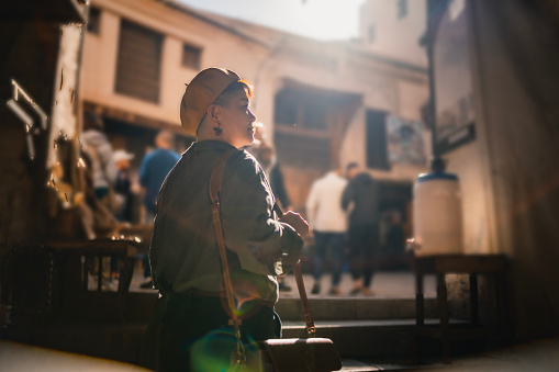 backlit Asian Chinese female tourist walking in souk market streets of Fez, Morocco