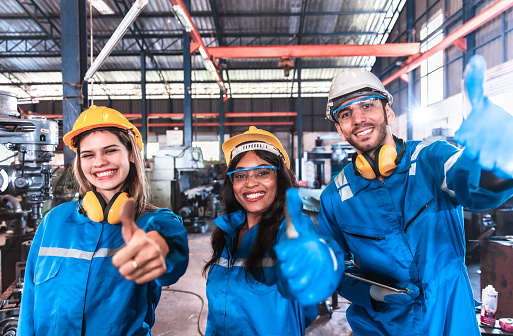 Young people worker in protective uniform operating machine at factory Industrial.People working in industry.Portrait of Female Engineer looking camera at work place.