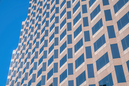 Modern office building in Austin Texas with windows reflecting the blue sky. City skyline with view of the commercial or housing unit facade against blue sky background.