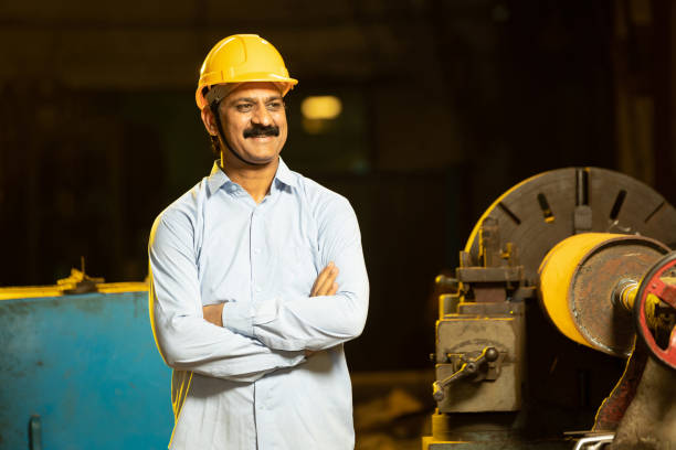istock Indian Mechanical Engineer wearing safety yellow hard hat smiling while standing cross arm. Industrial factory worker concept. 1448067248