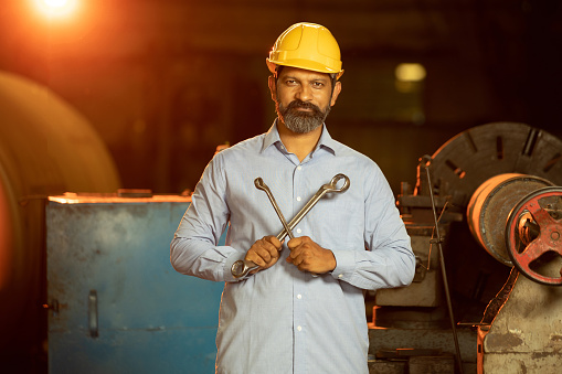 Indian man wearing yellow helmet working on machine in Industrial factory, Beard Male mechanical worker, maintenance repair machine,  skill india.