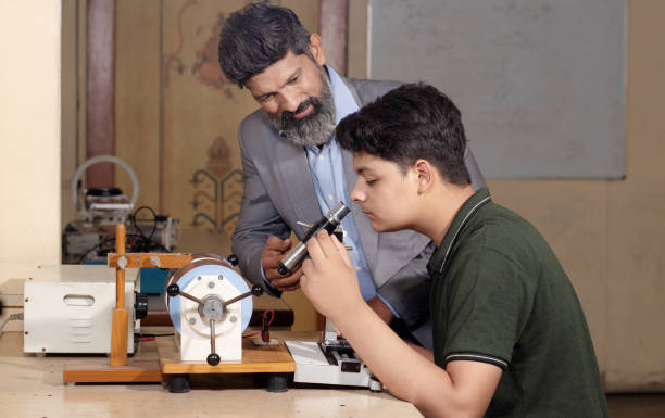 istock Indian male teacher and student working or experimenting in science lab. 1448069394