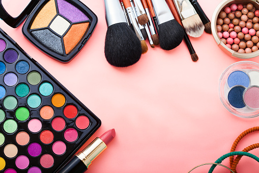 Colorful cosmetics for make up on pink background. Top view.