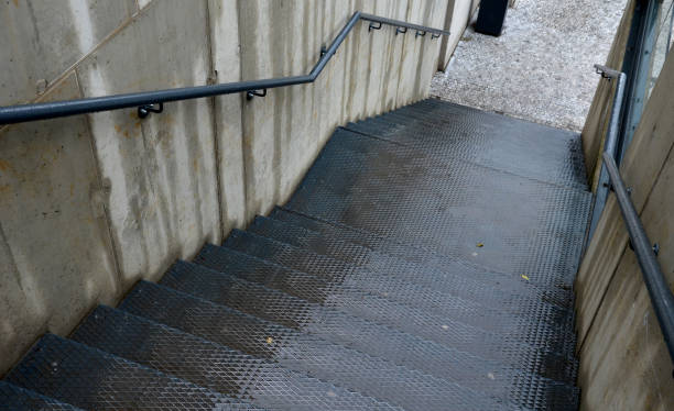 istock concrete walls between which a metal staircase with an anti-slip pattern is wedged. the railing on the exposed concrete is painted black. 1448073342