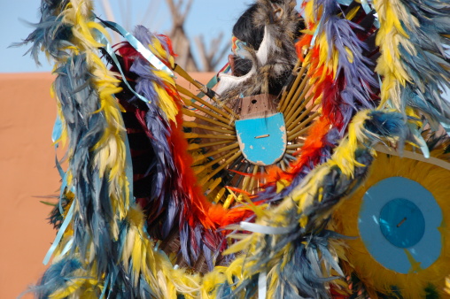 Two Bald Eagles fly near an American Indian with his paint horse on a tall cliff in a mountainous area.