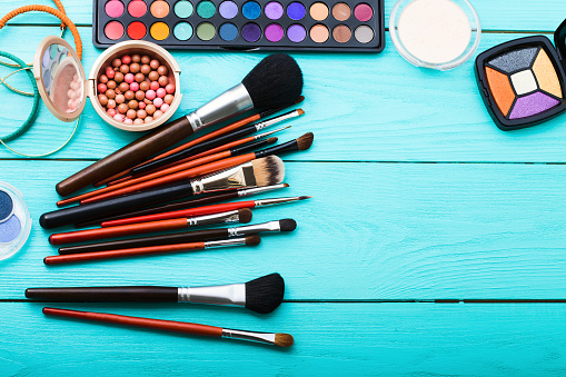 Makeup tools on blue wooden background. Top view, copy space. Woman beauty accessories. Eye shadows.