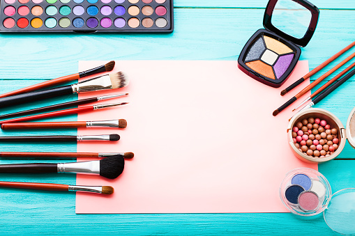 Makeup tools on blue wooden background. Top view, copy space. Woman beauty accessories. Eye shadows.
