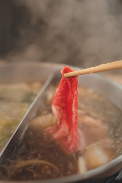 istock Using chopsticks to bring the fresh beef to the Sukiyaki pot. 1448078922