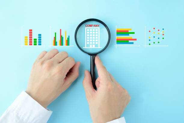 istock Human's hands using magnifying glass with company pictogram and business graphs,analyzing company performance image 1448079039