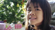 istock Young Asian girl looking at camera with Christmas tree in the background. 1448079223