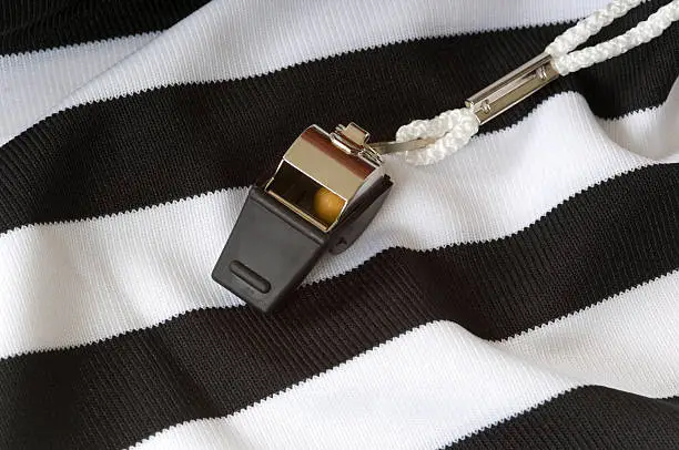 A referee's striped jersey and a whistle 
