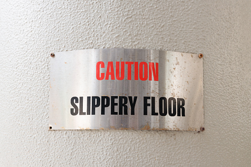 Metal sign on a wall to warn of a slippery floor