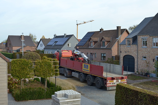 Leuven, Vlaams-Brabant, Belgium - October 28, 2022: sitting truck driver starts engine on mobile crane to transport construction materials on the lorry truck