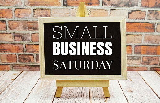 Small Business Saturday typography text on the blackboard set on wooden floor and brick background