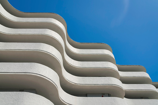 Low angle view of a building with curved walls under the clear blue sky at Miami, Florida. Building exterior with painted white balcony walls.