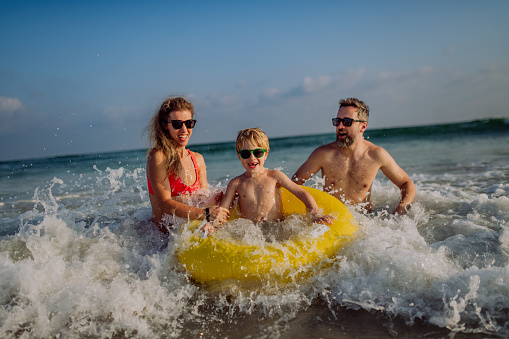 Happy family with little son enjoying time in the sea in exotic country.