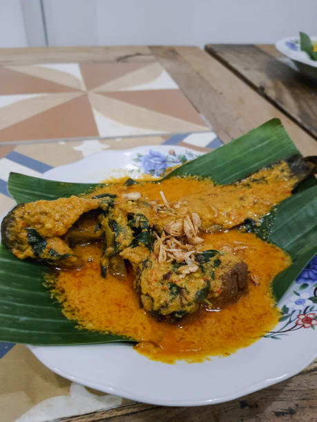 A serving of catfish mangut is served on a plate with banana leaves. stock photo