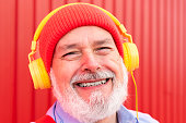 close-up portrait of a happy hipster retiree listening to music with headphones
