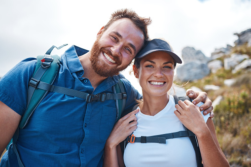 Hiking, couple and adventure being health, outdoor and enjoy nature with smile, happy and bonding together. Hike, man and woman being active, healthy and mountain range for wellness, workout and fun.