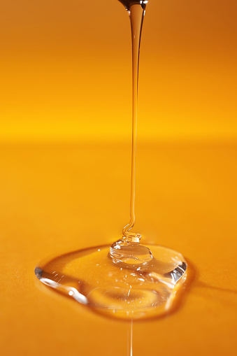 Una gota de gel corporal o champú que se vierte desde arriba sobre un fondo amarillo saturado. photo