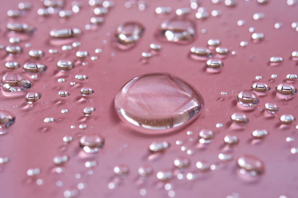 istock A large drop and splashes of micellar water on a pink background. 1448099828