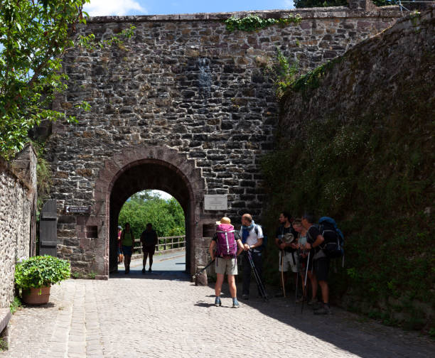 Pilgrims next to the historic Porte Saint-Jacques along the Way of St. James Saint-Jean-Pied-de-Port, France - July 27, 2022: Pilgrims next to the historic Porte Saint-Jacques along the Way of St. James saint jean pied de port stock pictures, royalty-free photos & images