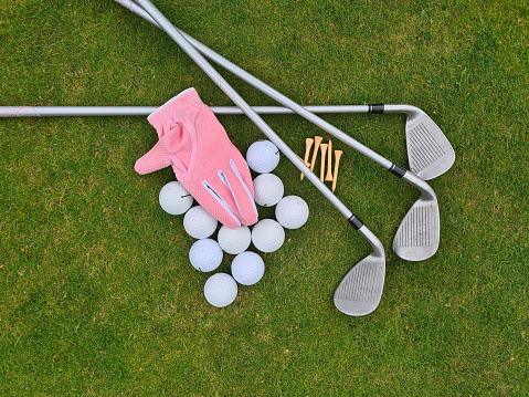 Golf equipment on green grass on golf course. Flat lay golf club balls tee gloves