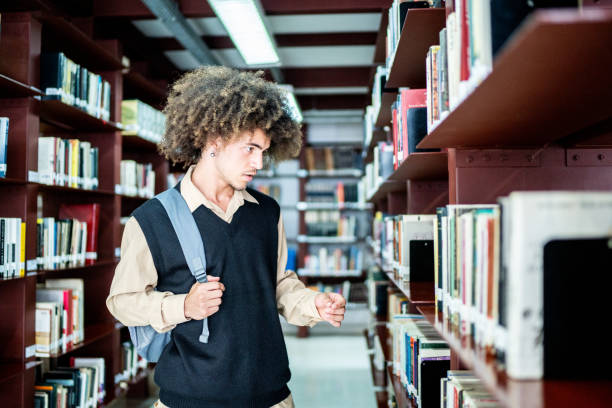 istock Young student man choosing a book from the bookshelf at a library 1448106770