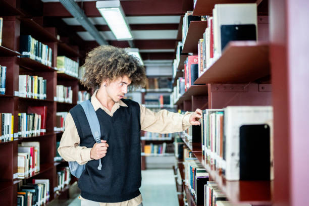 istock Young student man choosing a book from the bookshelf at a library 1448106776