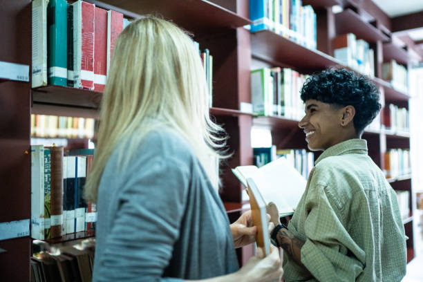 istock Friends talking and reading book in a library's corridor 1448106891