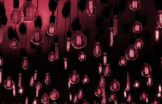 Retro Edison lamp on Viva Magenta ceiling background. Conceptual idea.