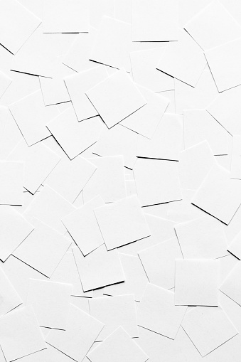 Pile of blank pieces of paper scattered around forming a white neutral background