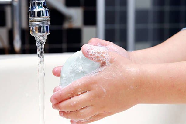 Hands washing with a bar of soap under the faucet stock photo