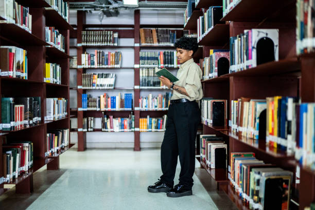 istock Young woman reading a book in a library 1448114377