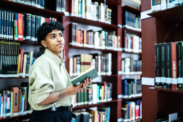 istock Young woman looking for book in a bookshelf at a library 1448114397