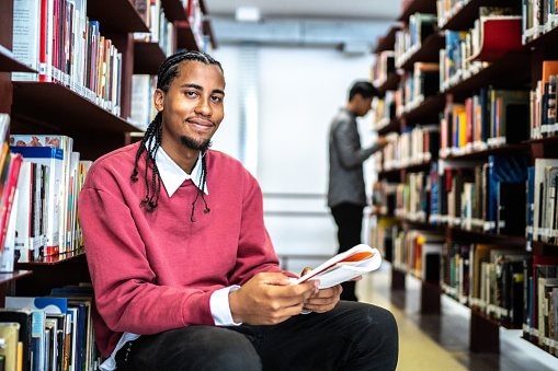 Portrait of a young man reading a book in the library