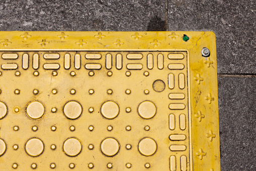 Pattern of circles and lines on a yellow rubber mat to prevent slipping on a sidewalk.