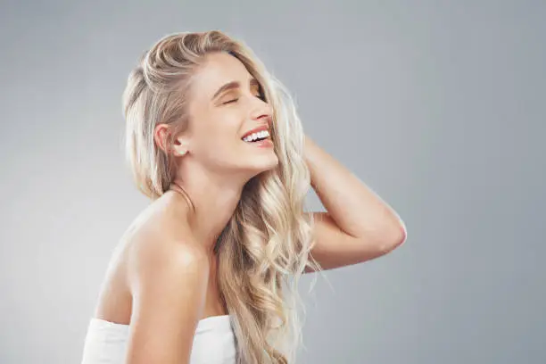 Photo of Hair care, woman and smile being happy, head and confident being content, proud and with grey studio background. Young female, girl or touch hair for wellness, natural beauty or happiness being bare