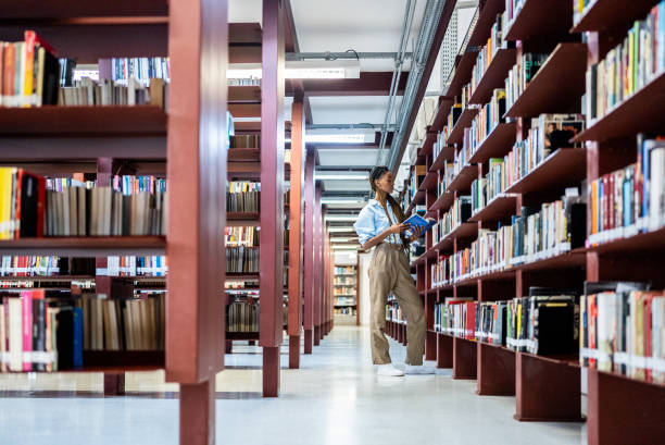 istock Young woman searching books in the library 1448121470