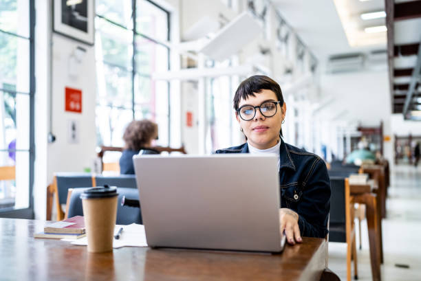 istock Transgender woman using the laptop in the library 1448121507