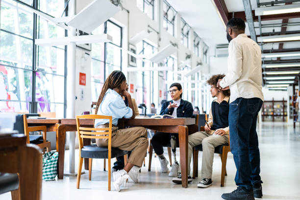 istock Teacher helping students in the library - including transgender woman 1448121790