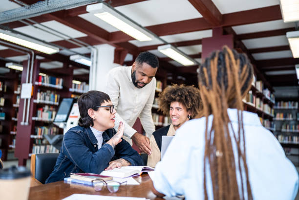 istock Teacher helping students in the library - including transgender woman 1448121849