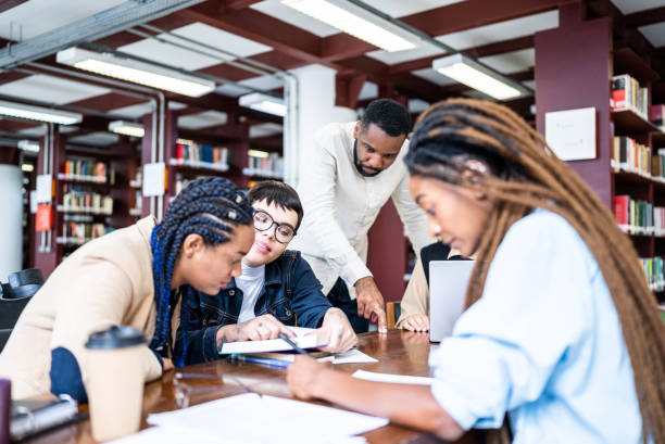istock Teacher helping students in the library - including transgender woman 1448121875